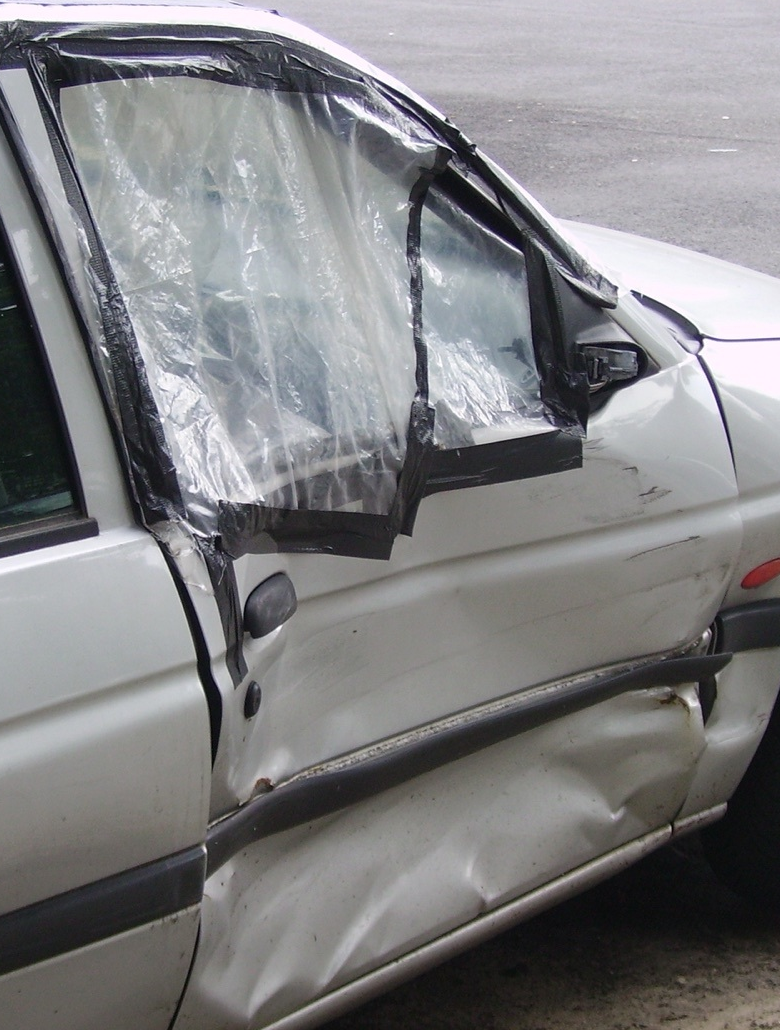 Large detail crop of the original passenger-door deformation and damaged window area; no damage pixels have been retouched.